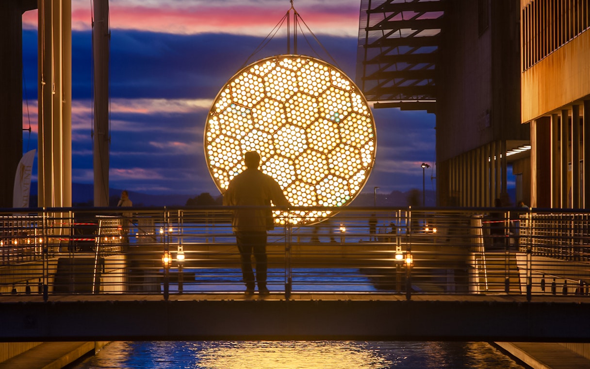 Man viewing illuminated art installation during Amsterdam Light Festival cruise.