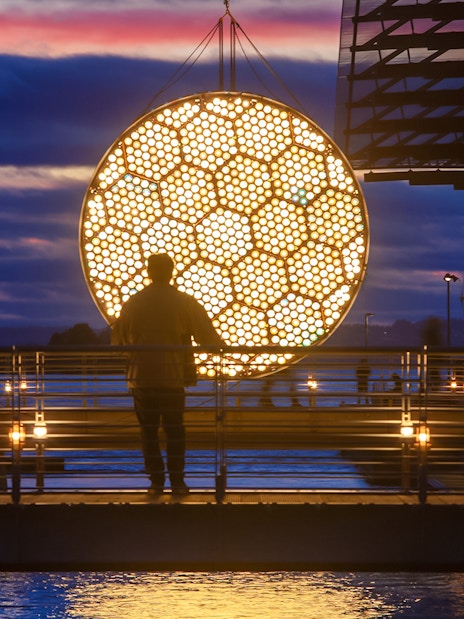 Man viewing illuminated art installation during Amsterdam Light Festival cruise.