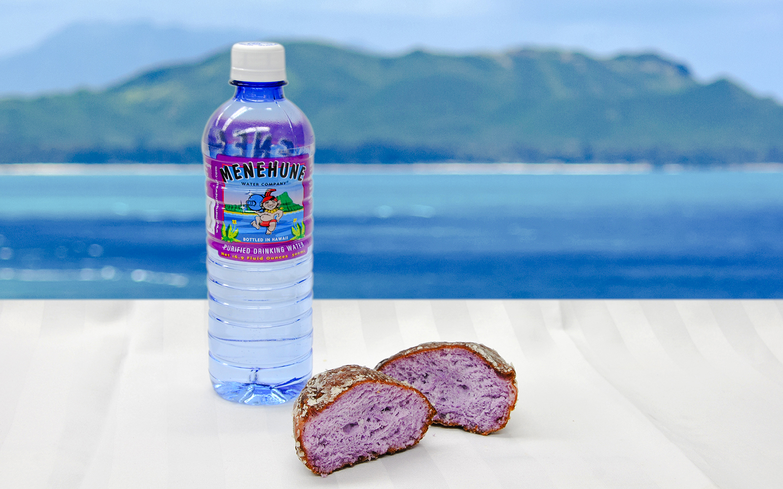 Poi malasada and Hawaiian water bottle with ocean view in Hawaii.