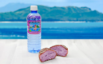 Poi malasada and Hawaiian water bottle with ocean view in Hawaii.