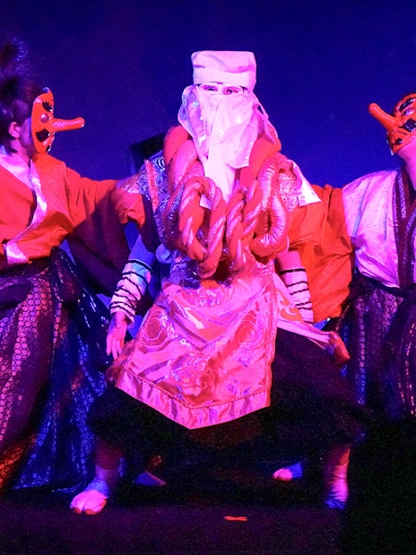 Performers in traditional costumes and masks at a Japanese festival dance show in Tokyo.