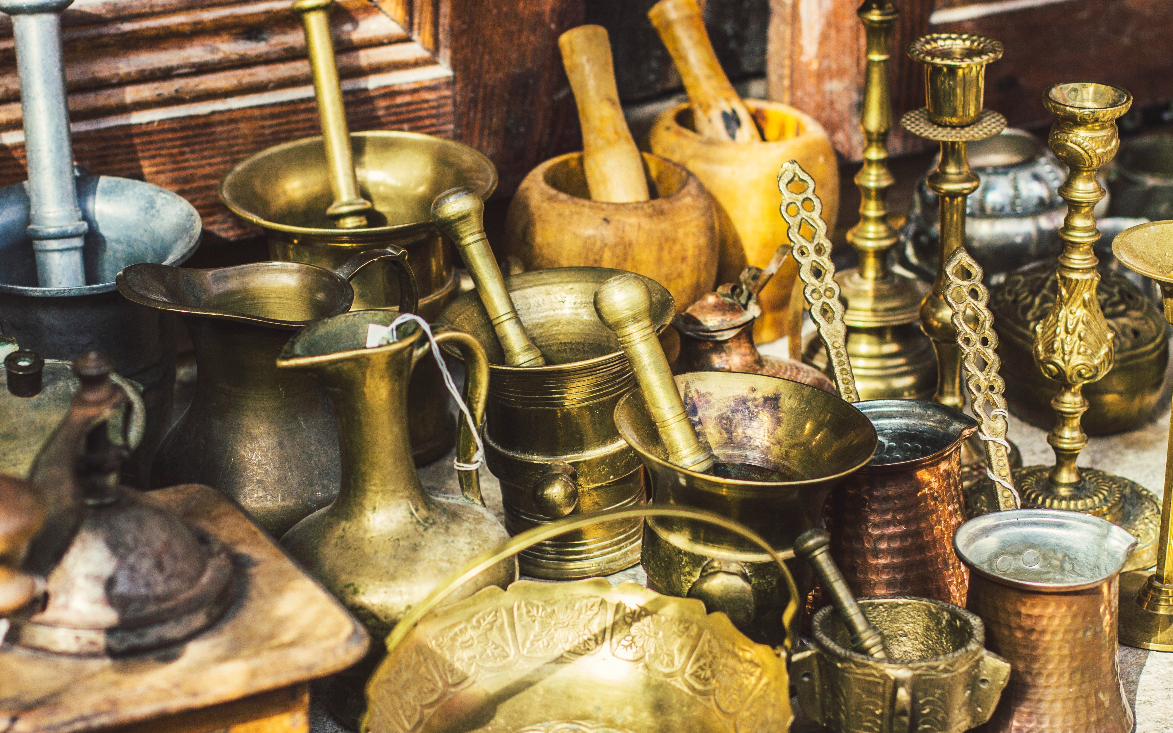 Antique utensils at Kruja flea market, Albania, featuring coffee mill, Turkish cezvas, bronze bowls.