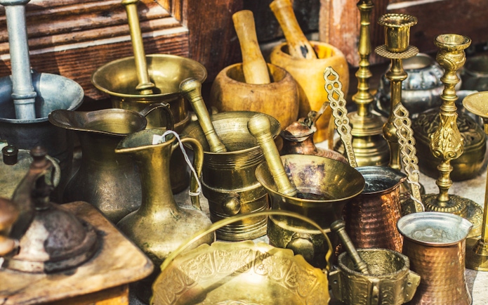 Antique utensils at Kruja flea market, Albania, featuring coffee mill, Turkish cezvas, bronze bowls.