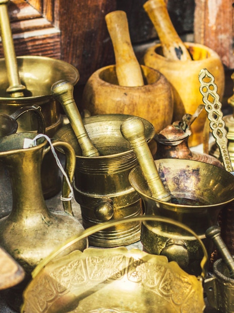 Antique utensils at Kruja flea market, Albania, featuring coffee mill, Turkish cezvas, bronze bowls.