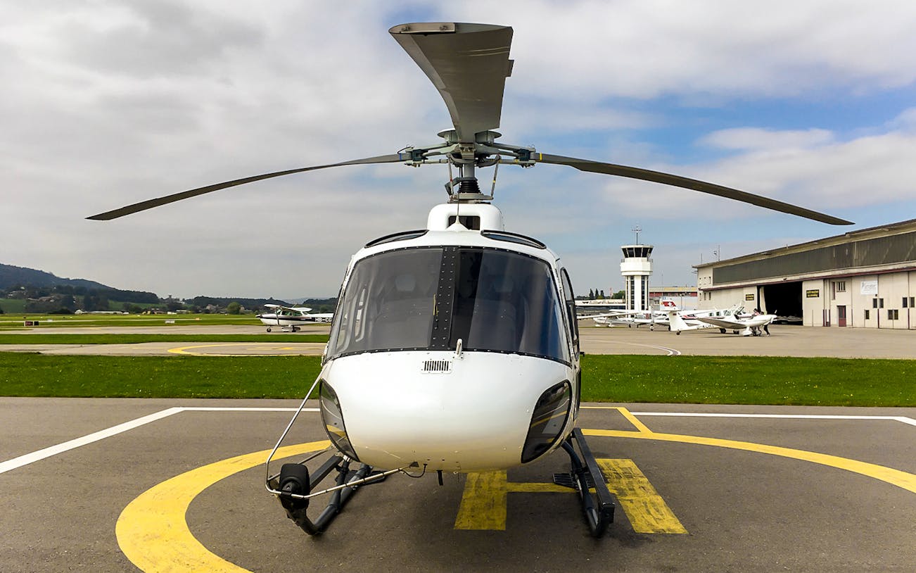Private helicopter on a helipad ready for a scenic flight to the Swiss Alps.