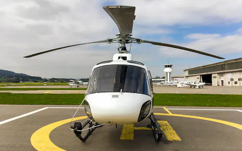 Private helicopter on a helipad ready for a scenic flight to the Swiss Alps.