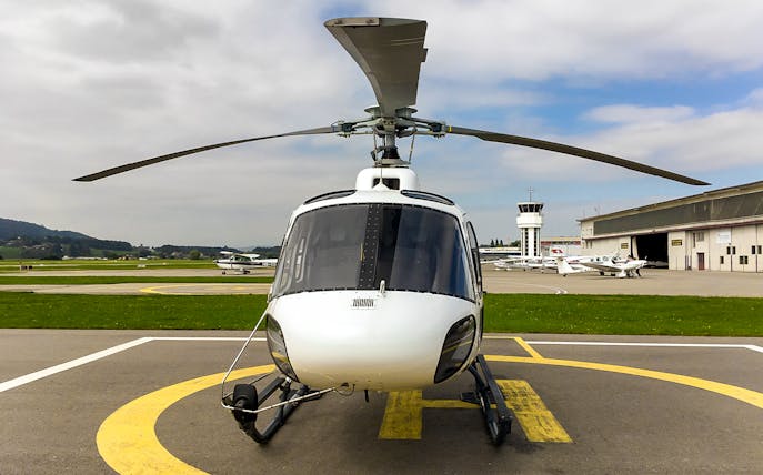 Private helicopter on a helipad ready for a scenic flight to the Swiss Alps.
