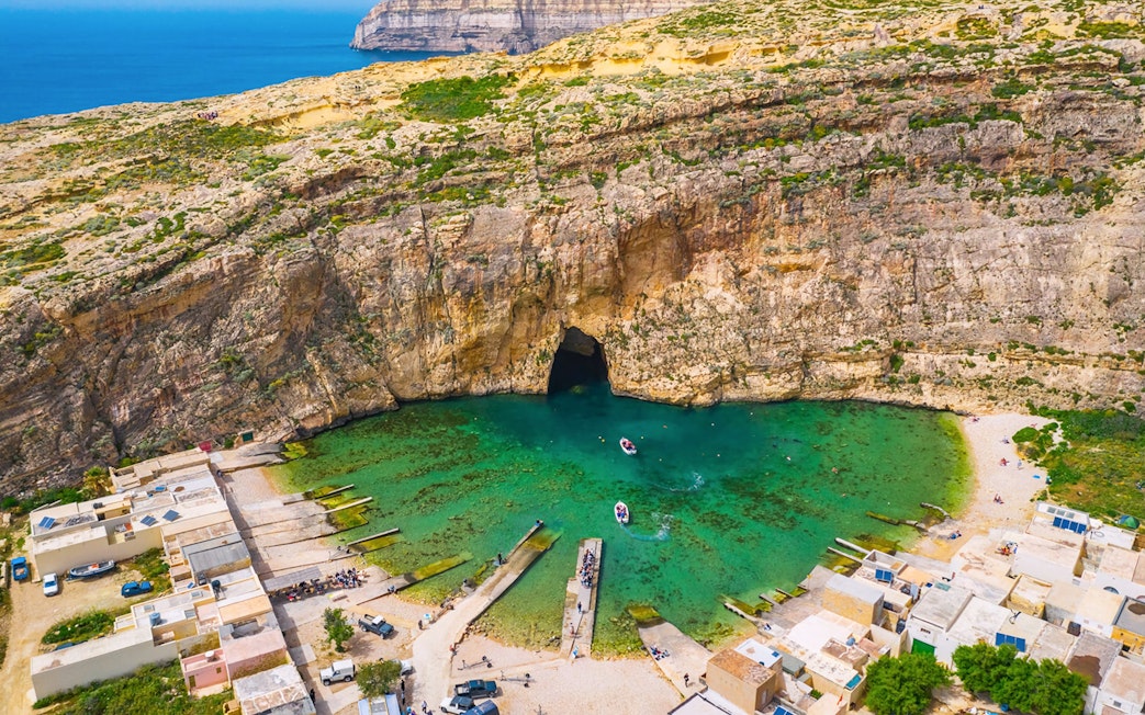 Dwejra Inland Sea with boats near rocky cliffs, Gozo, Malta.