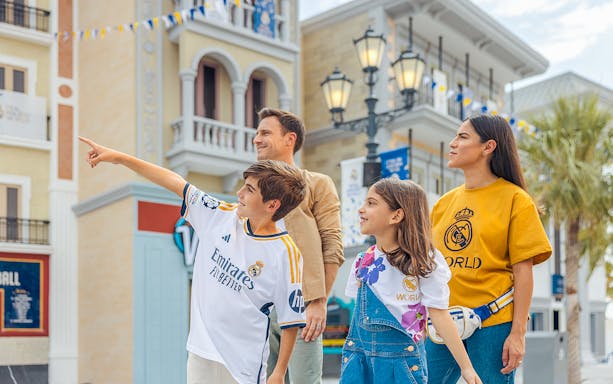 Family exploring Real Madrid World, child pointing at attractions.