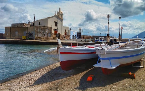 Boats docked near a church on Lipari Island, Italy, during a tour to Salina.