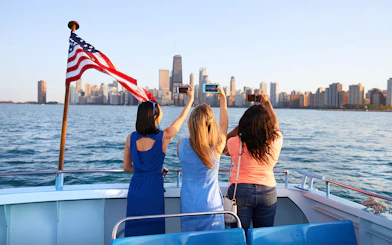 Tourists photographing Chicago skyline from a boat on the Chicago River & Lake Sightseeing Cruise.