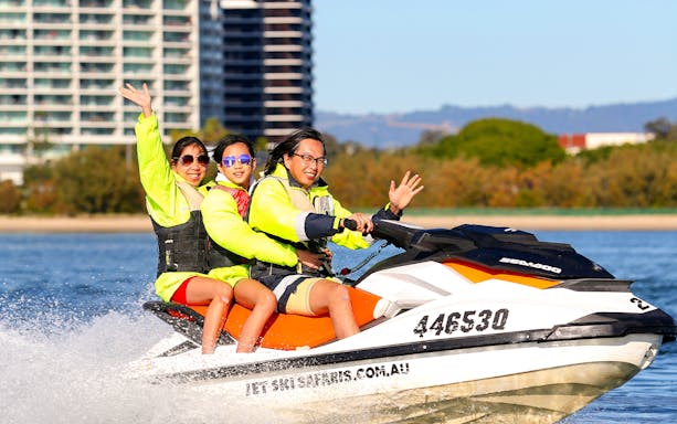 Family enjoying a jet ski ride near city waterfront.