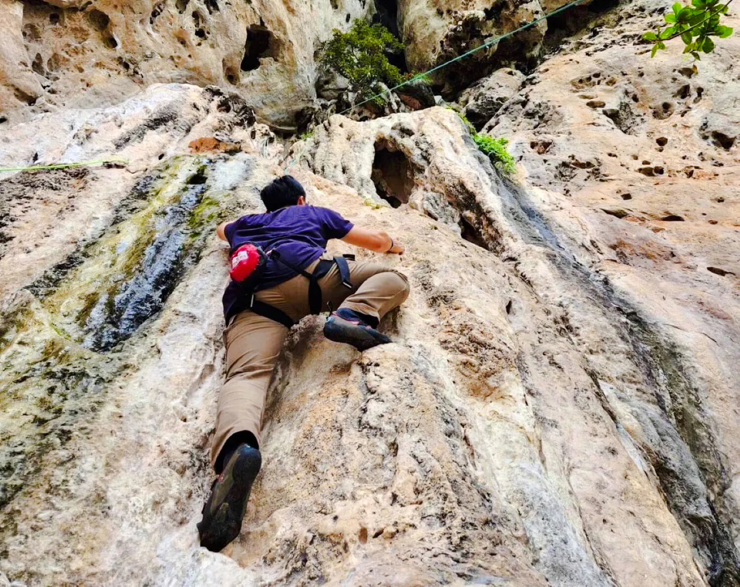 Climber ascending limestone cliff at Railay Beach, Krabi.