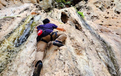 Climber ascending limestone cliff at Railay Beach, Krabi.
