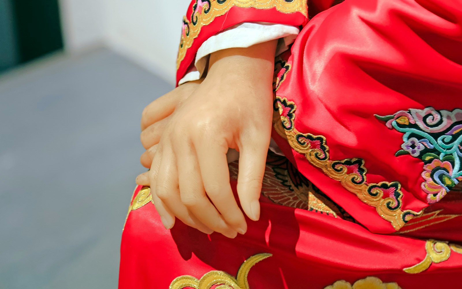 Wax figure in red embroidered robe at wax museum.