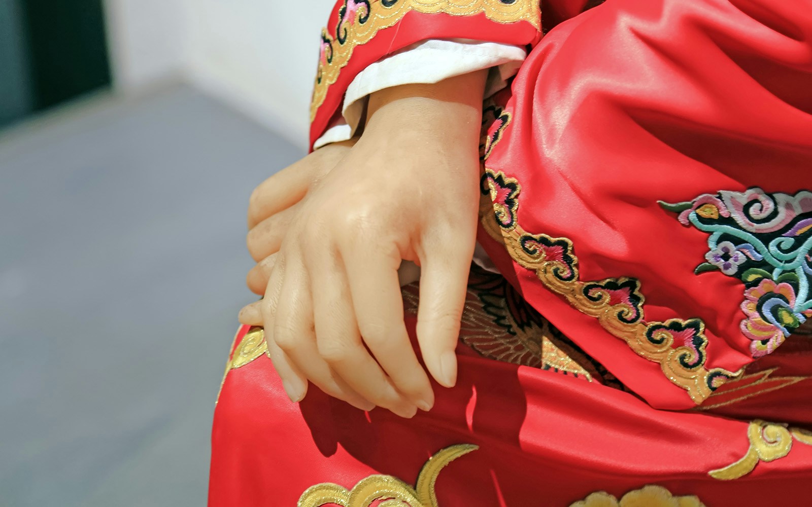 Wax figure in red embroidered robe at wax museum.