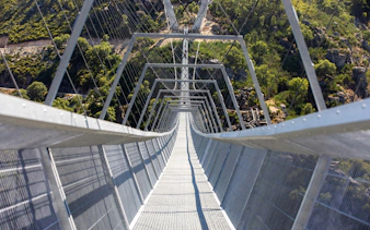 Pedestrian view of 516 Arouca suspension bridge spanning a lush valley in Portugal.