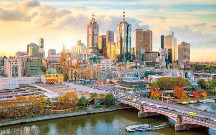 Melbourne skyline with Yarra River and city buildings at sunset.