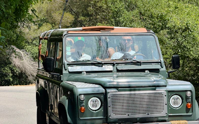 Land Rover driving through lush greenery for wine tasting tour in historic Nice château.