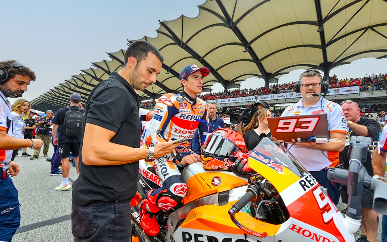 Motorcycle racer and team at Petronas Grand Prix of Malaysia 2023 starting line.