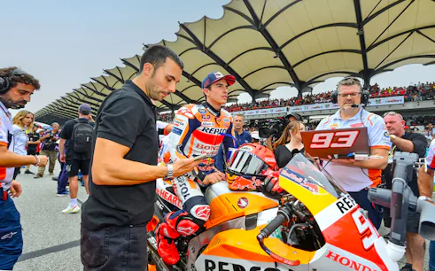 Motorcycle racer and team at Petronas Grand Prix of Malaysia 2023 starting line.