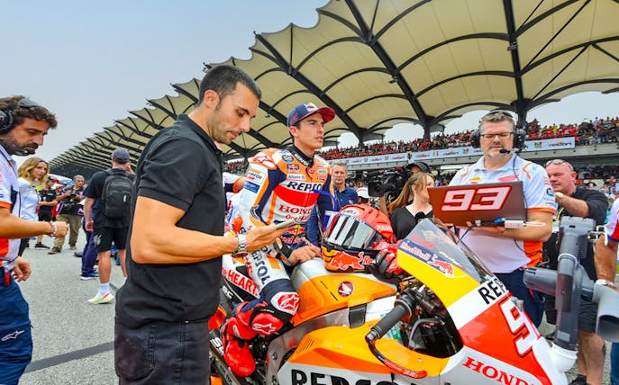 Motorcycle racer and team at Petronas Grand Prix of Malaysia 2023 starting line.