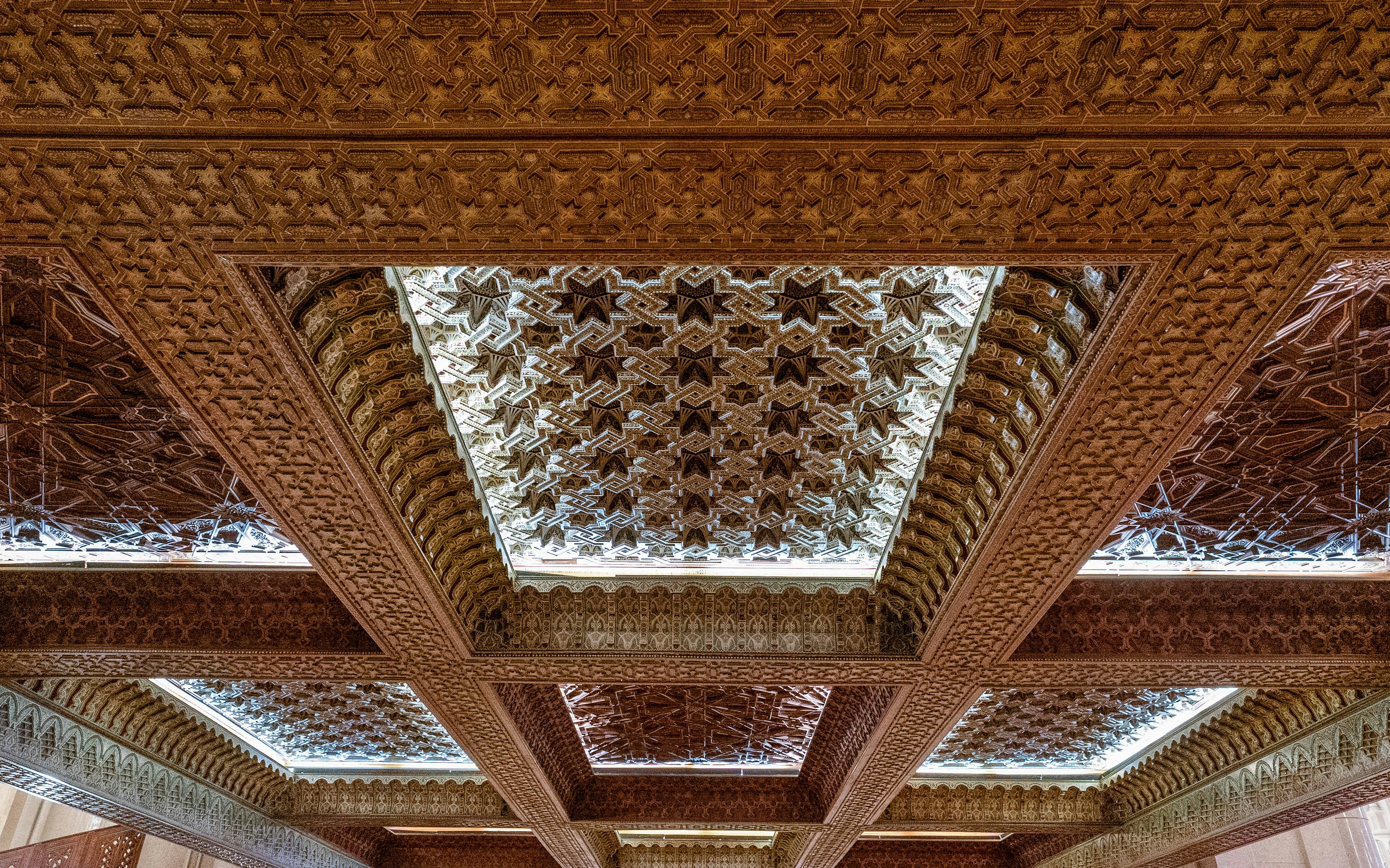 Hand-carved cedarwood ceilings with intricate patterns in Hassan II Mosque, Morocco.