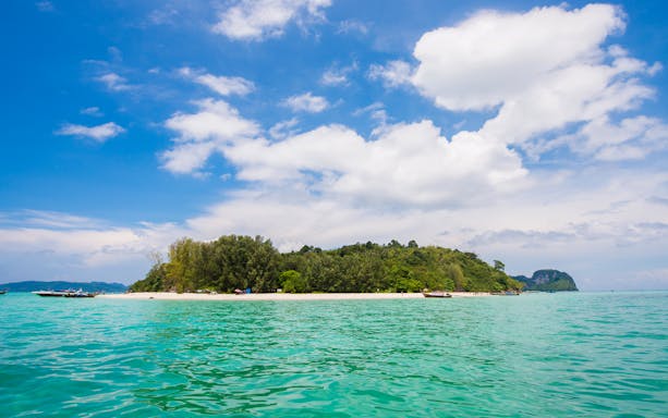 Phi Phi island beach with turquoise water and boats during sunrise tour.