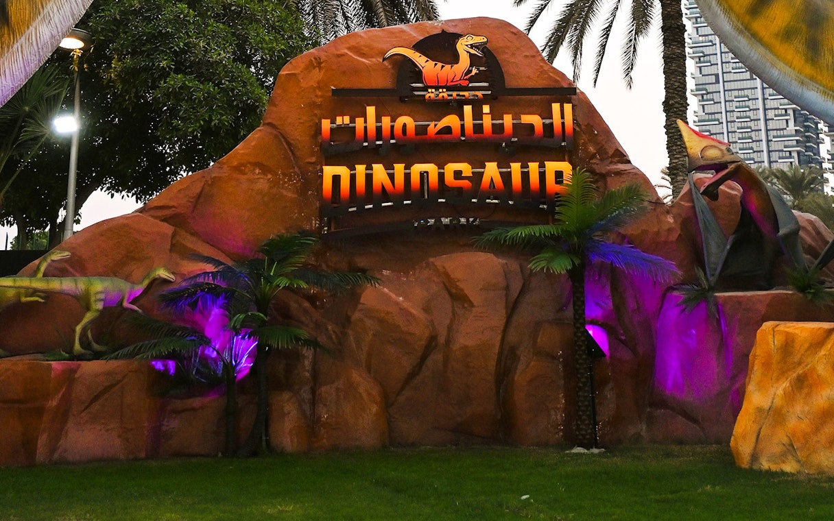 Dinosaur sculptures and sign at Dubai Garden Glow.