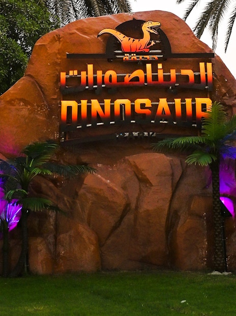 Dinosaur sculptures and sign at Dubai Garden Glow.