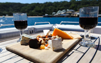Cheese platter and wine on a table during Sydney Harbour cruise with scenic view.