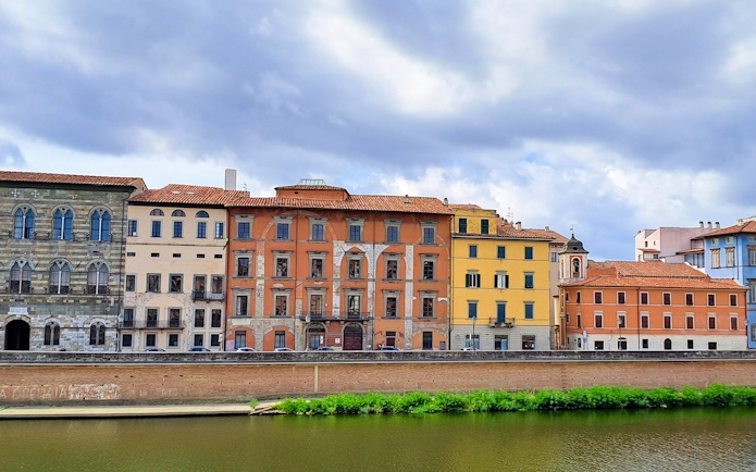 Colorful historic buildings along the Arno River in Pisa, Italy.