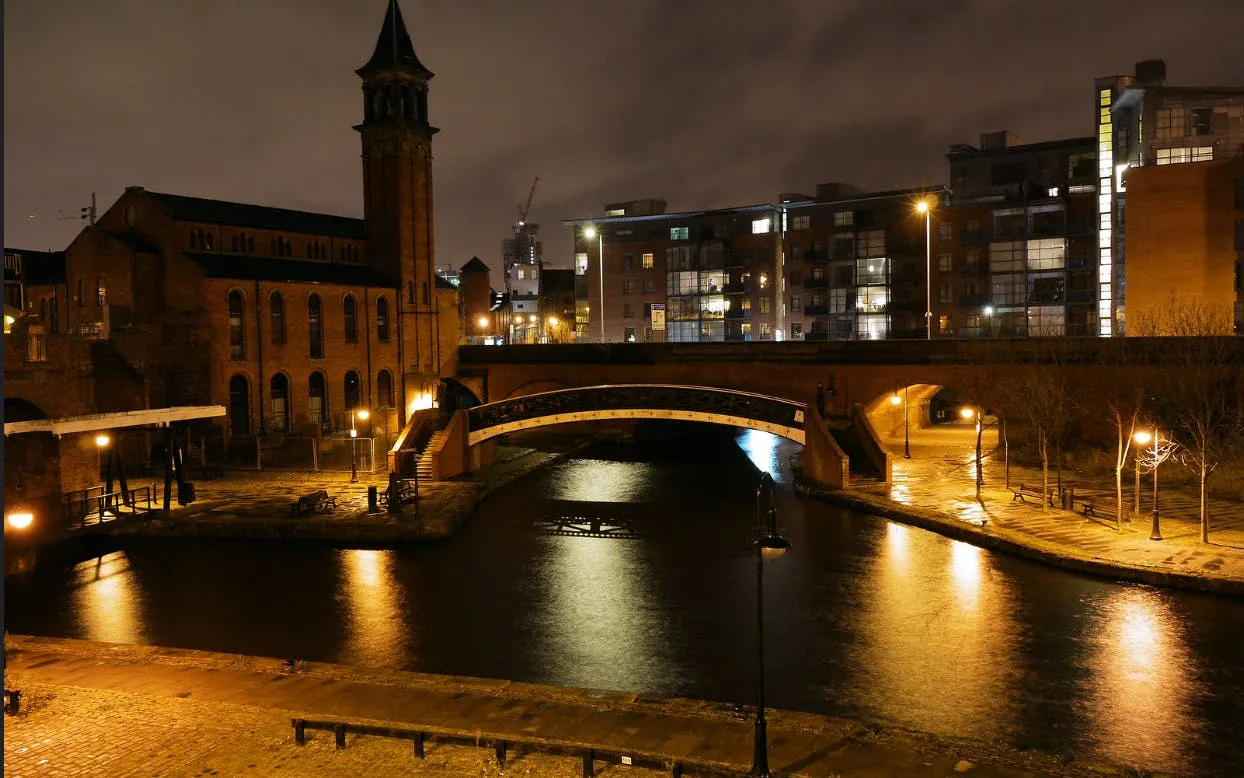 Historic canal and bridge in Manchester at night, part of the self-guided city exploration game.