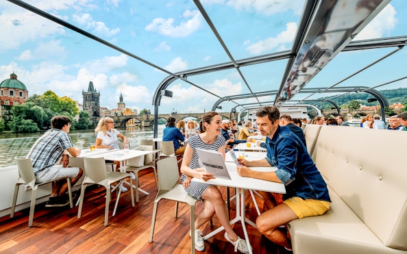 Vltava River cruise with passengers enjoying views of Prague landmarks.