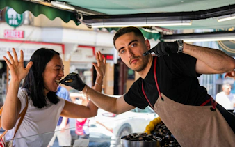 Vendor serving mussels to a woman at a street food stall during an Istanbul food tour.