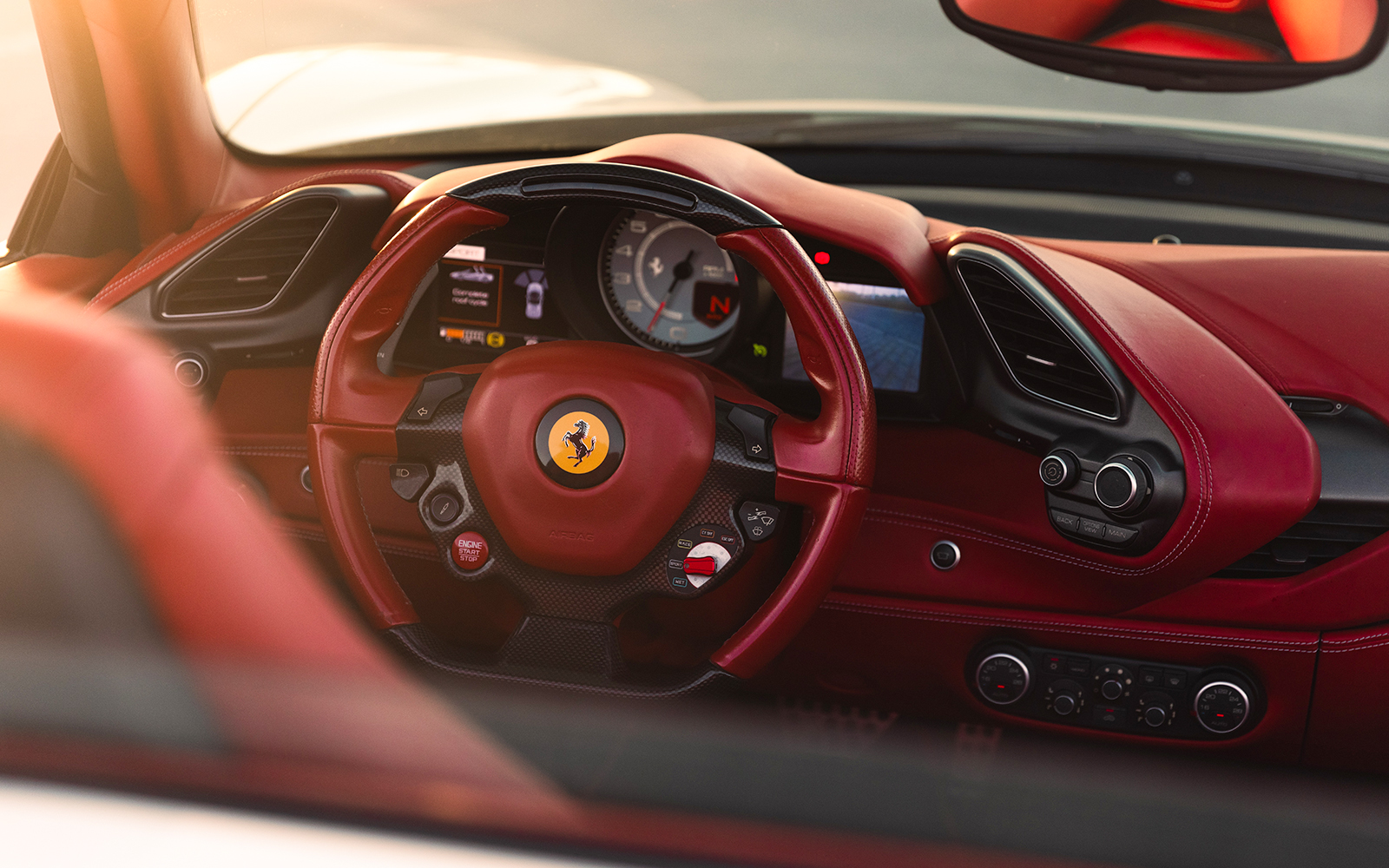 Ferrari interior with red leather steering wheel and dashboard controls.