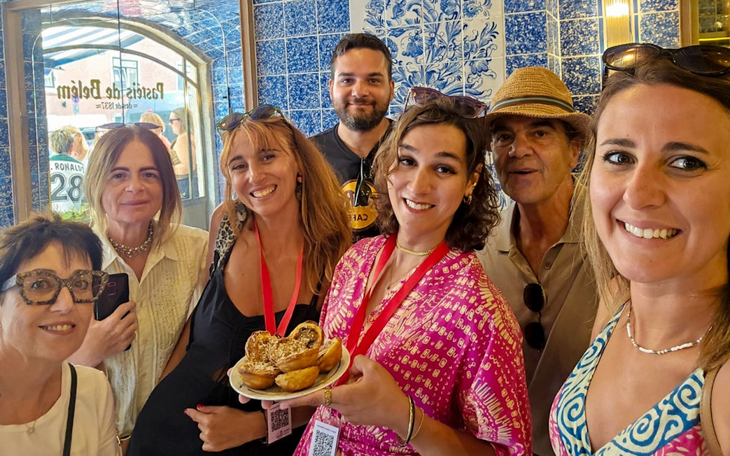 Tourists with a guide enjoying local pastries in a Lisbon bakery, Portugal.