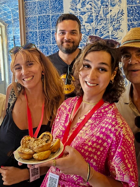 Tourists with a guide enjoying local pastries in a Lisbon bakery, Portugal.
