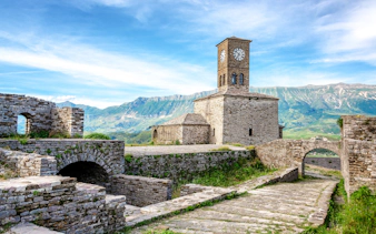 Clocktower at Gjirokaster Castle with mountain backdrop, Albania.