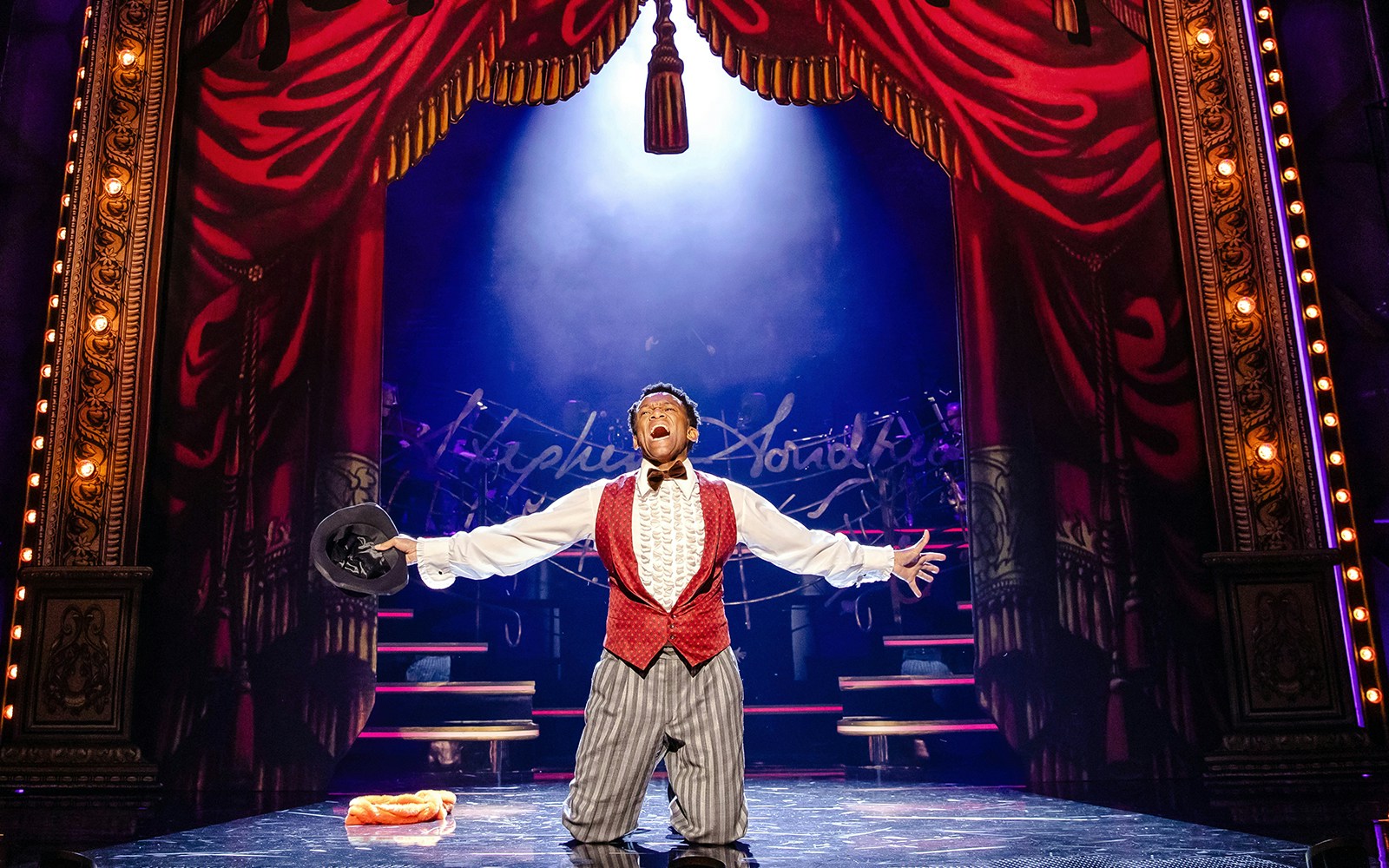 Performer on stage during Stephen Sondheim's Old Friends show, holding a hat under spotlight.