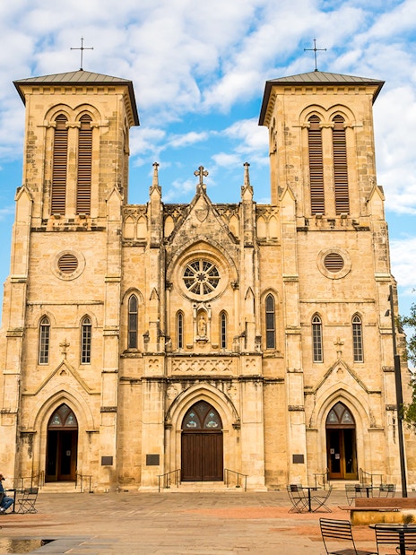 San Fernando Cathedral facade in San Antonio with plaza and trees.