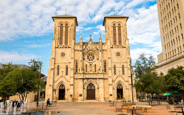 San Fernando Cathedral facade in San Antonio with plaza and trees.