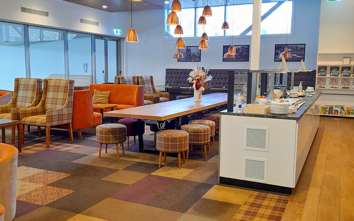 Manaia Plaza Premium Lounge seating area with buffet and modern decor.