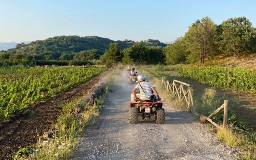 Quad bikes on a dirt path through Alcantara Gorges, Sicily, with lush greenery.