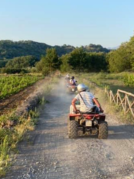 Quad bikes on a dirt path through Alcantara Gorges, Sicily, with lush greenery.
