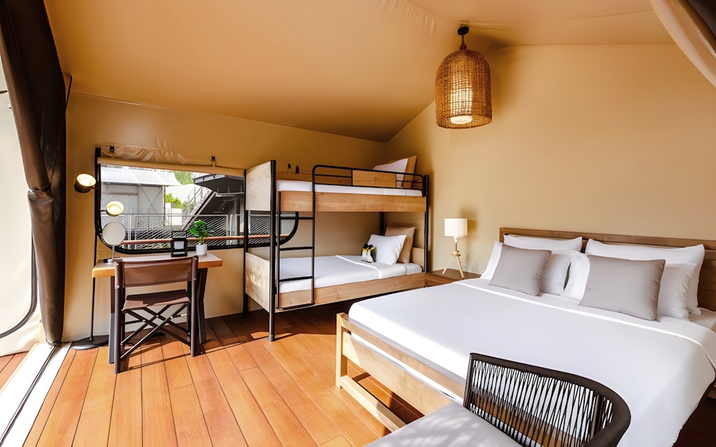 Interior of a tent at Colugo Camp, Mandai Wildlife Reserve, featuring a bed, bunk beds, and a desk.