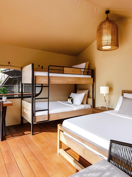 Interior of a tent at Colugo Camp, Mandai Wildlife Reserve, featuring a bed, bunk beds, and a desk.
