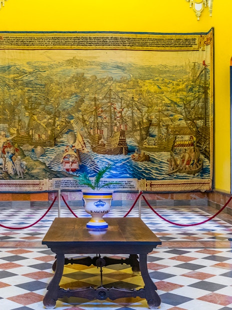 Tapestry room in the Alcazar of Seville displaying intricate maritime scenes.