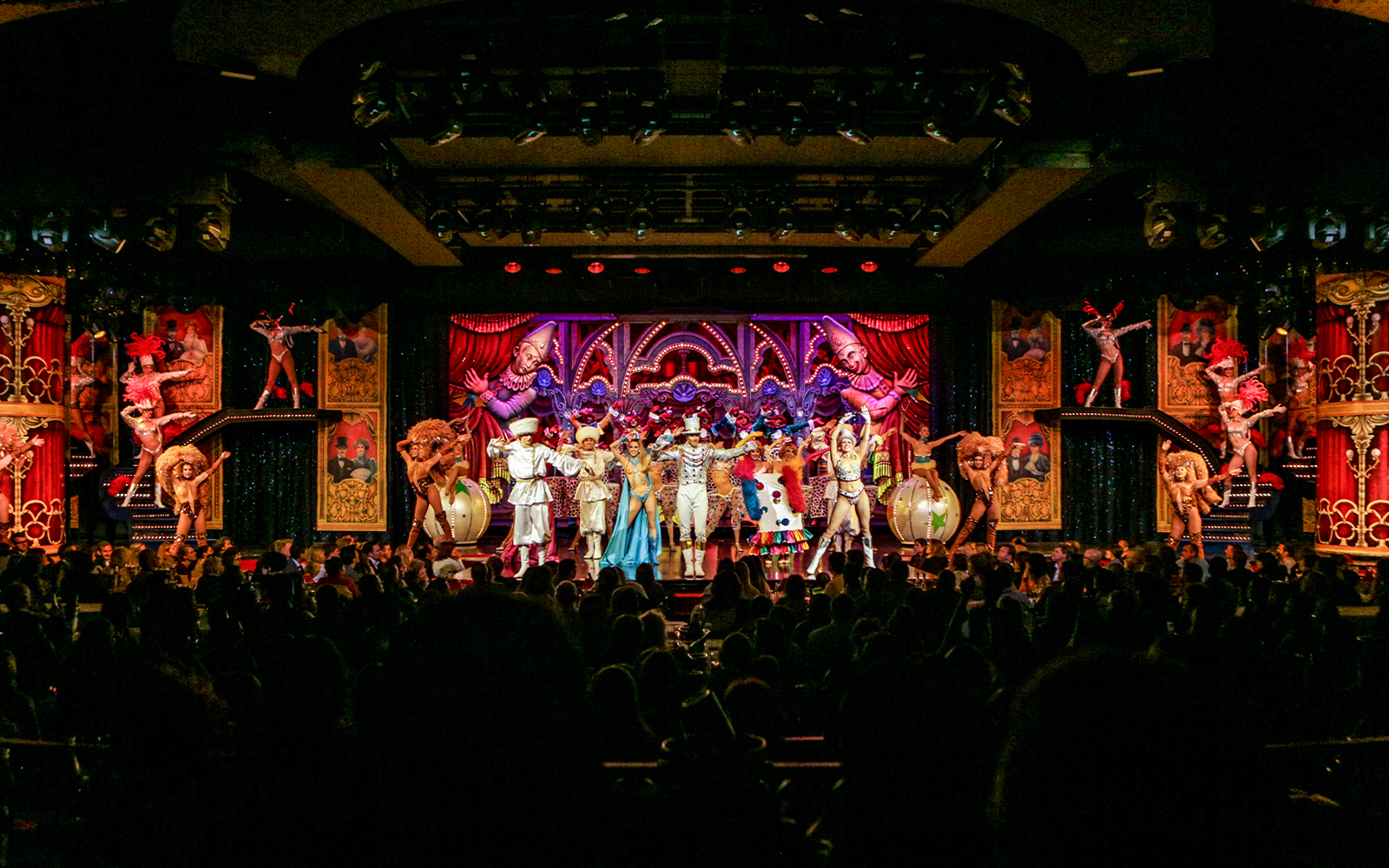 Performers on stage at the Moulin Rouge show in Paris, featuring vibrant costumes and elaborate set design.