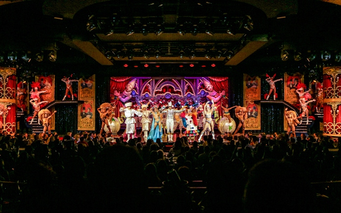 Performers on stage at the Moulin Rouge show in Paris, featuring vibrant costumes and elaborate set design.